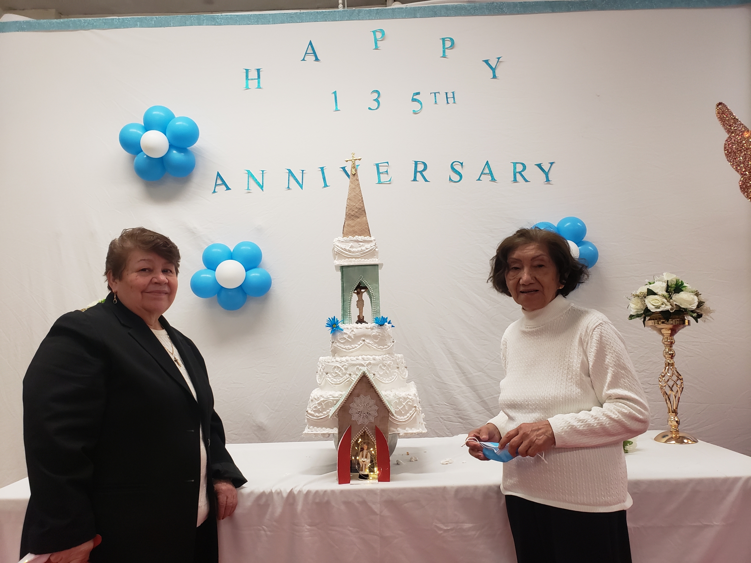 Two women standing in front of a cake.