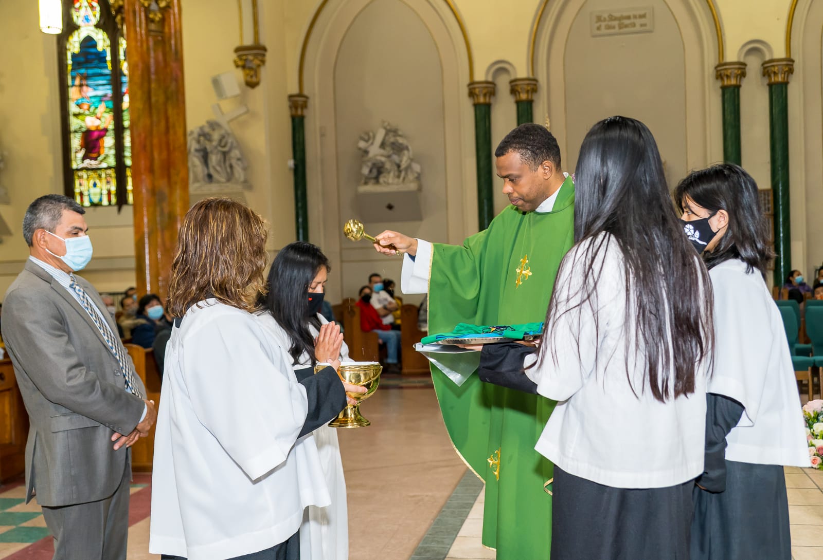 A priest is giving communion to people in the church.