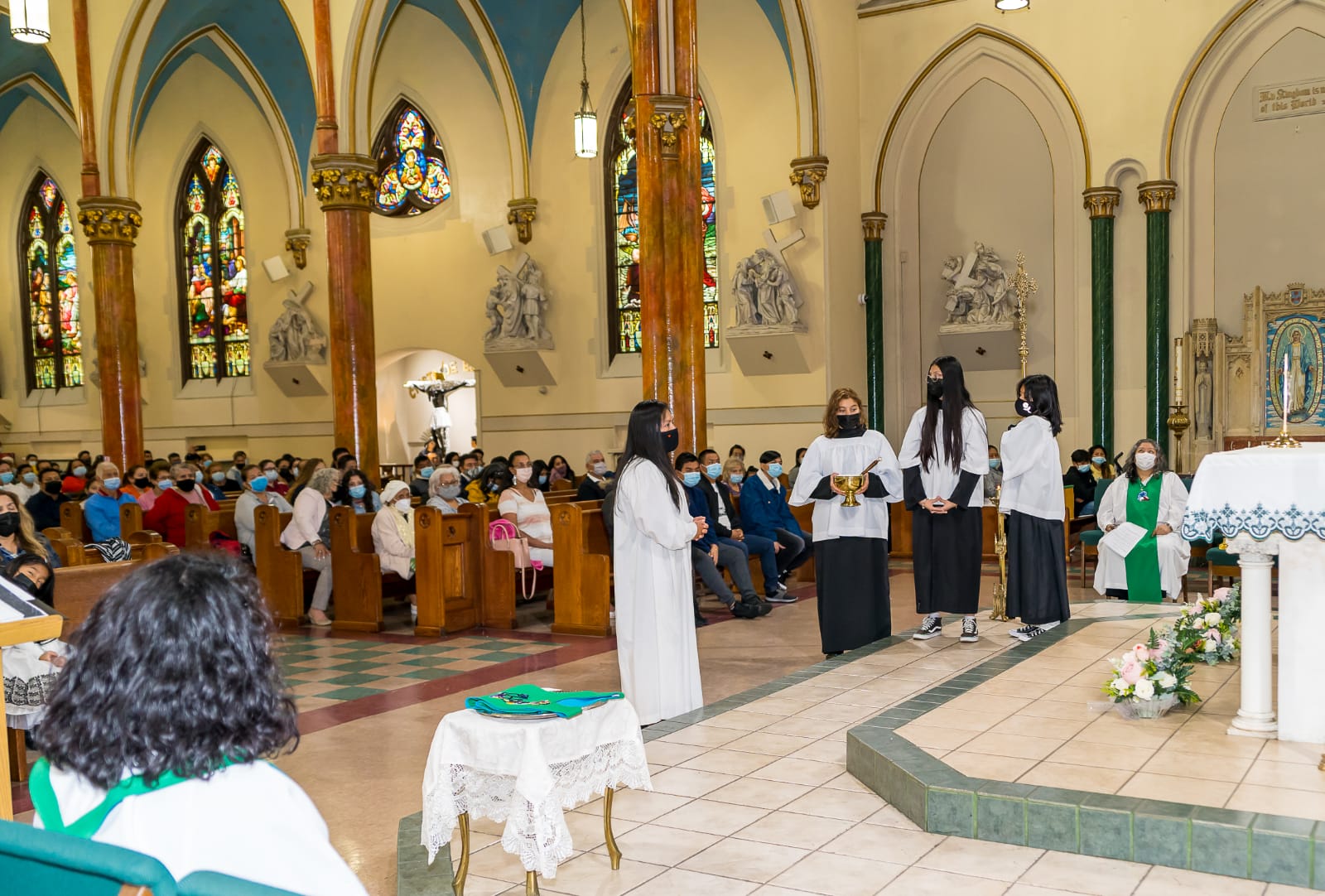 A group of people in white robes standing inside a church.
