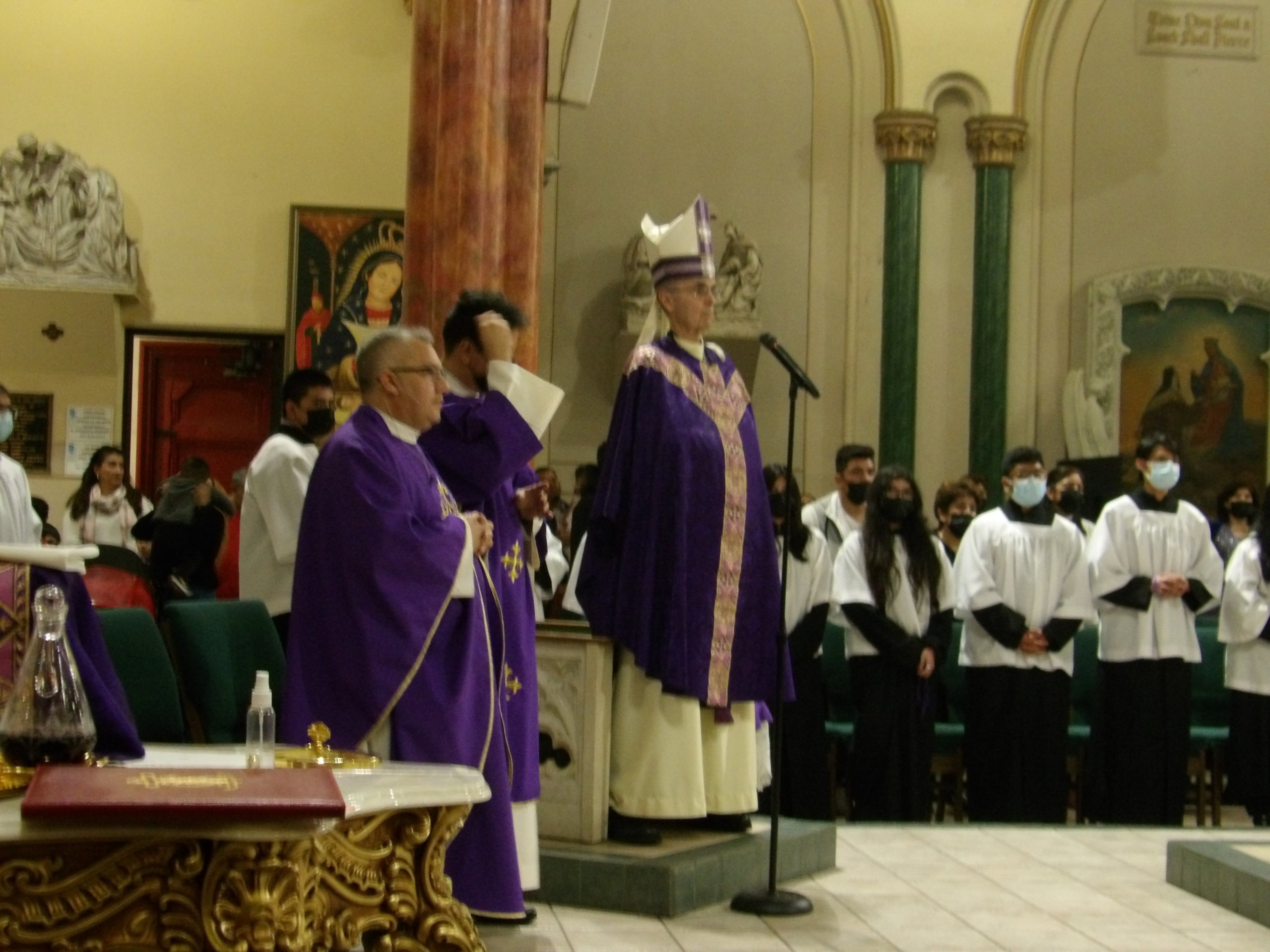 A priest is standing in front of the crowd.