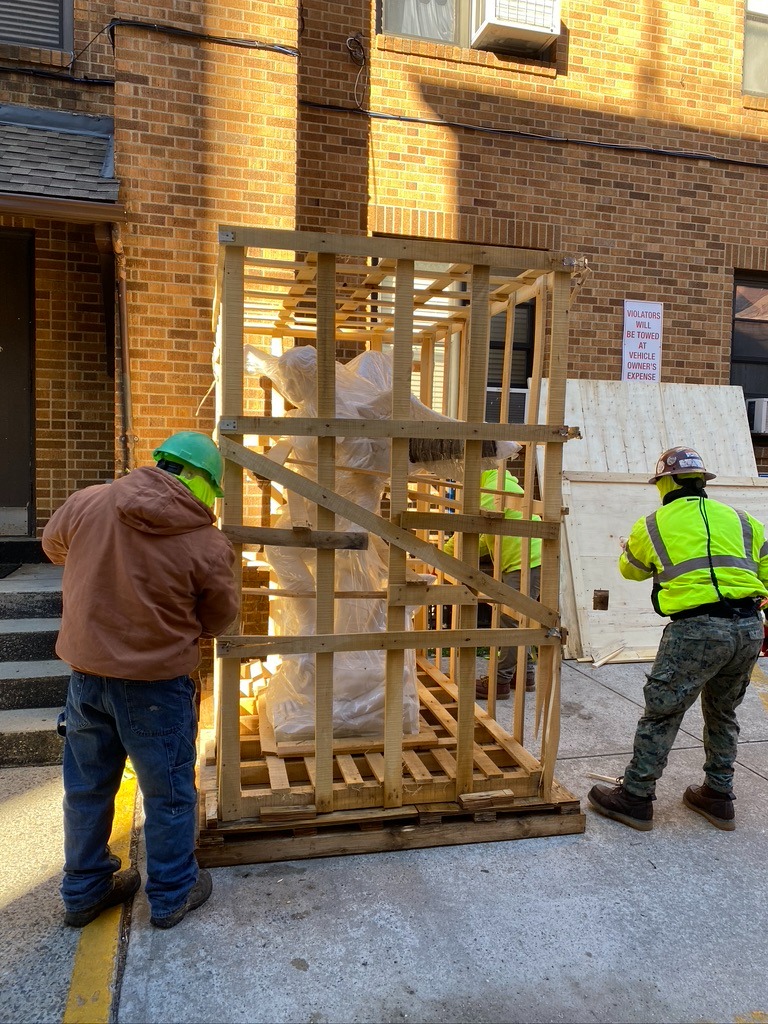 A group of men loading a crate onto a truck.