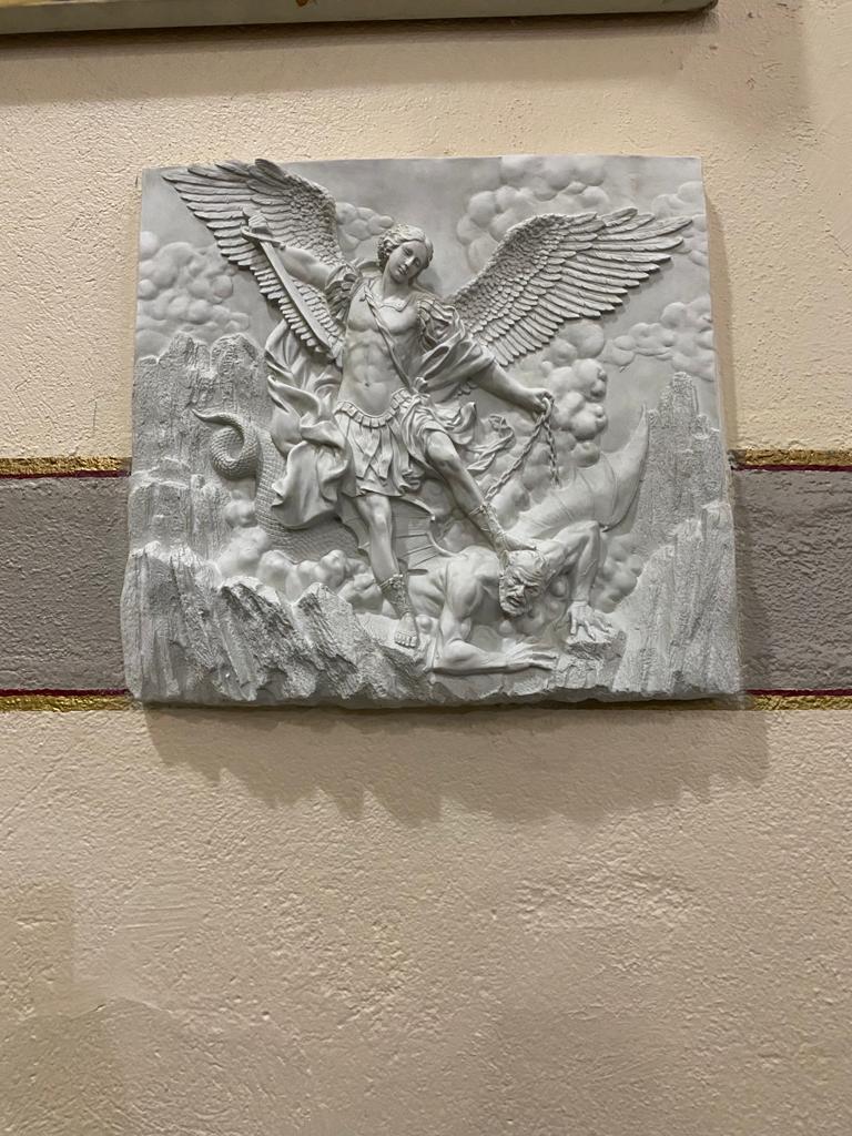 A white plaque with an image of st. Michael on it