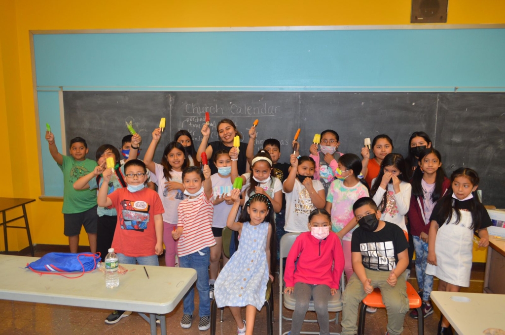 A group of children holding up plastic utensils.