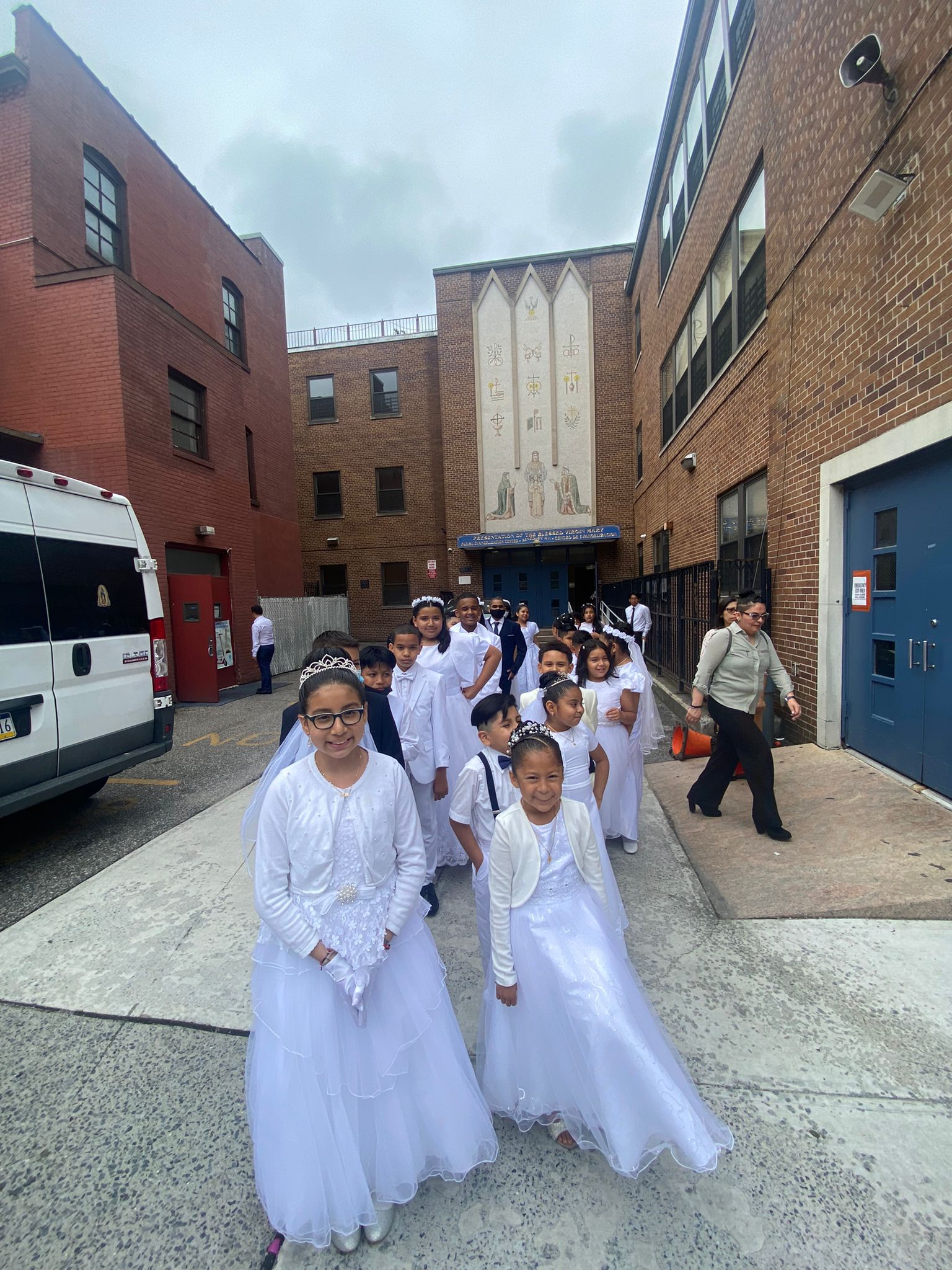 A group of young people in white dresses walking down the street.