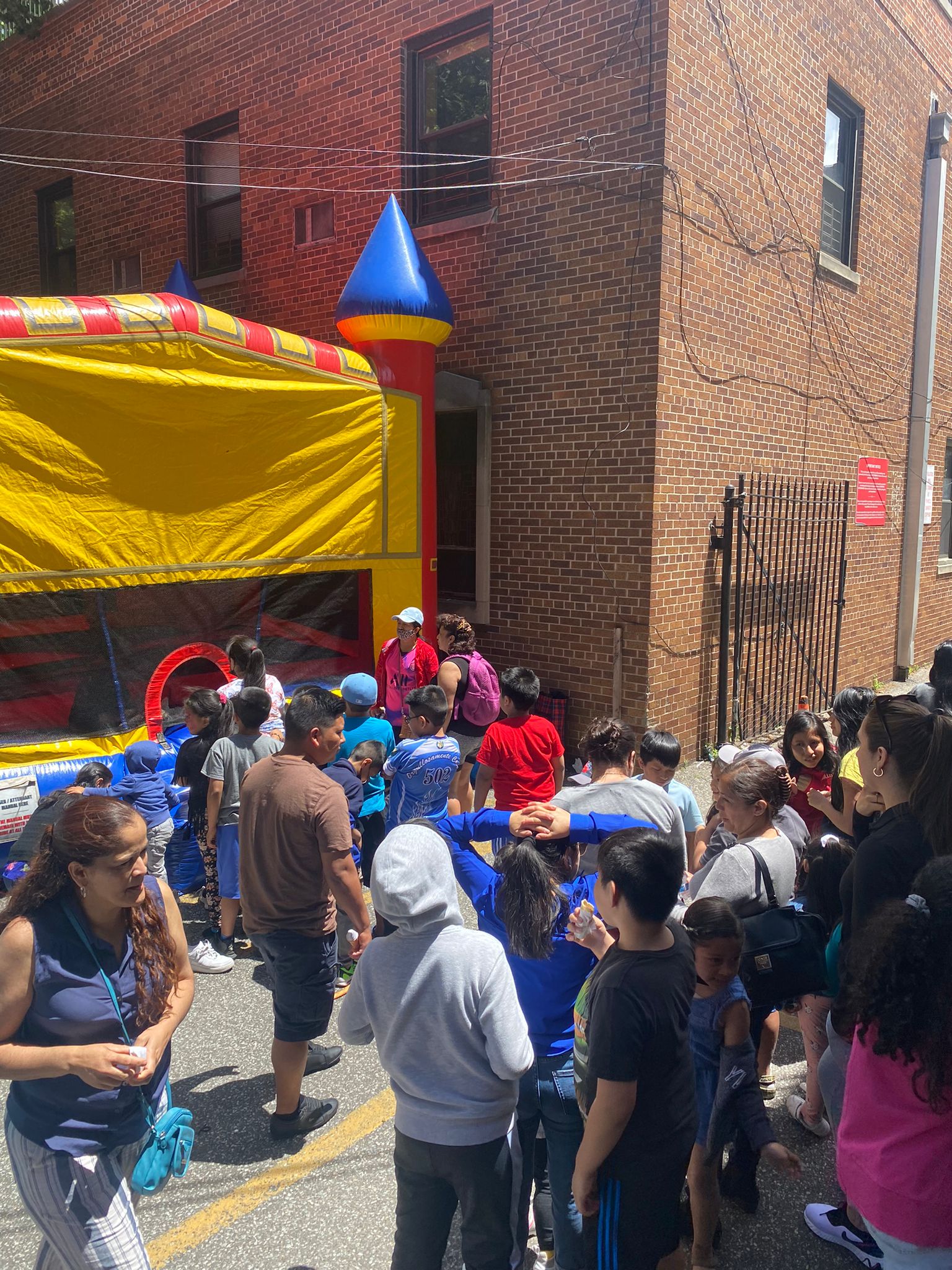 A crowd of people standing around an inflatable castle.