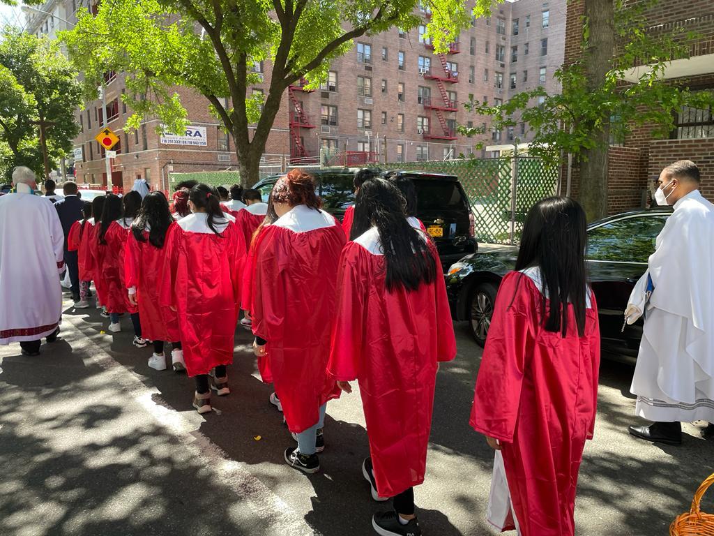 A group of people in red gowns are walking down the street.