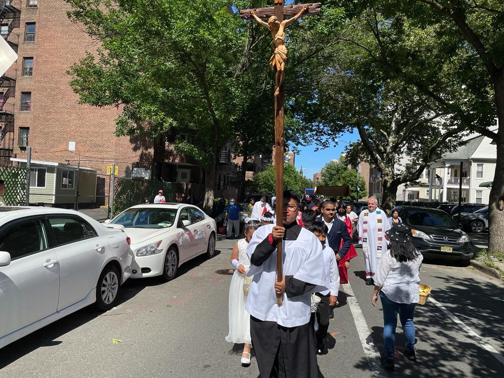 A man holding up a cross while walking down the street.