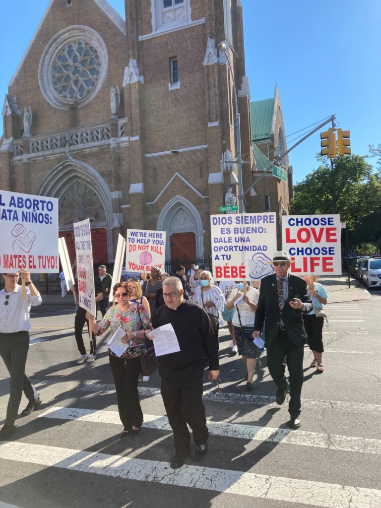 A group of people holding signs in front of a church.