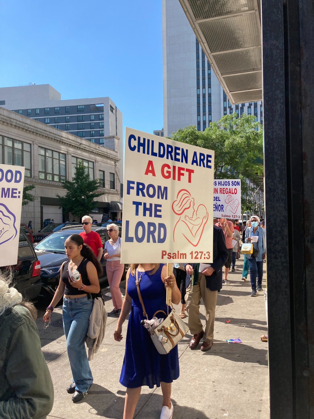 A woman holding up a sign that says children are a gift from the lord.