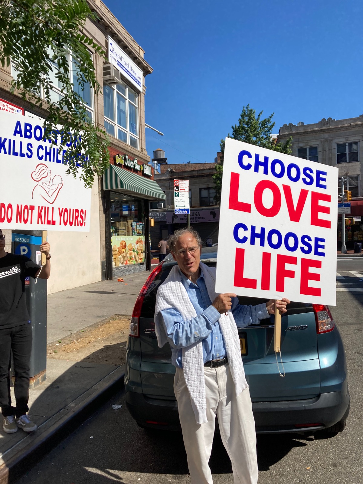 A man holding up a sign that says " choose love, choose life ".