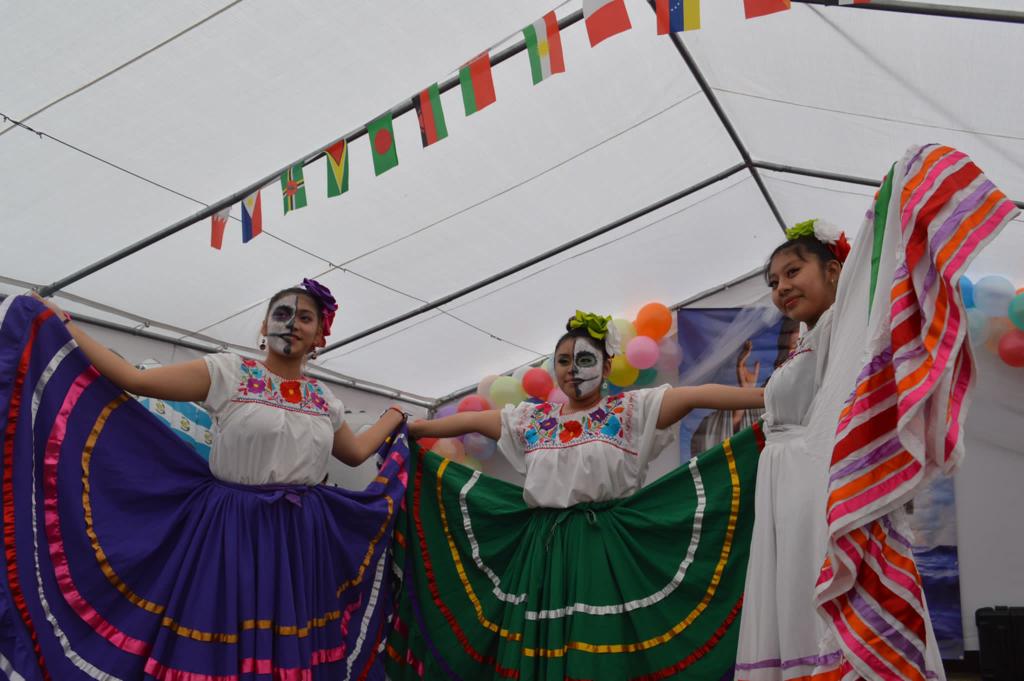 Three women in colorful costumes performing a dance.