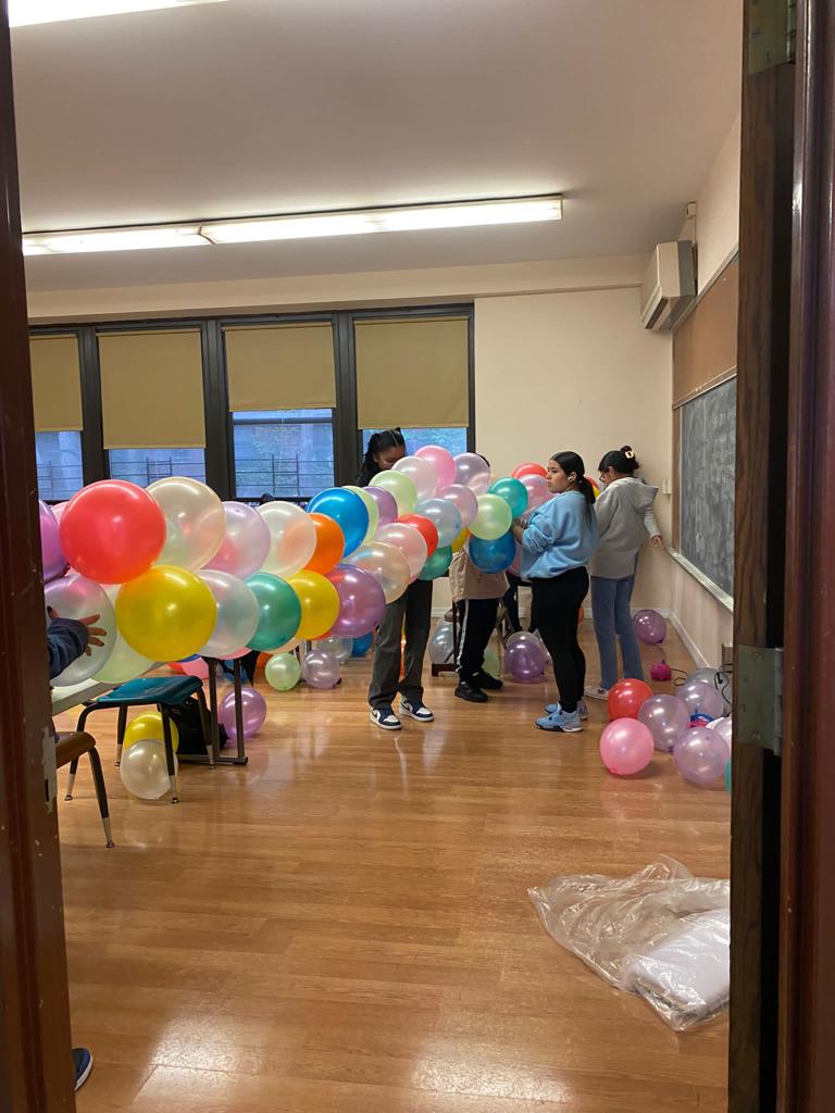 A group of people standing around balloons in the room.