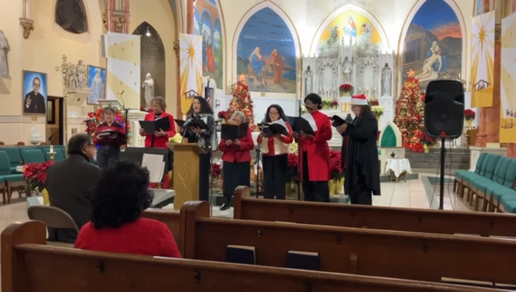 A group of people in red coats sing at the church.
